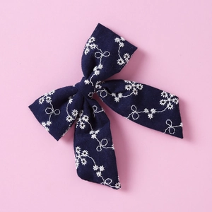 Détail d'un nœud papillon bleu marine en coton avec broderie florale blanche