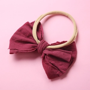 Détail d'un nœud en tissu bordeaux sur un bandeau pour bébé en nylon souple