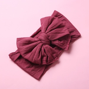 Close-up of soft wine red nylon baby headband with a large decorative bow detail