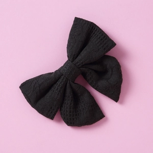 Nahaufnahme der schwarzen Jacquard-Baumwoll-Haarspange mit Spitzenstruktur auf Rosa Grund