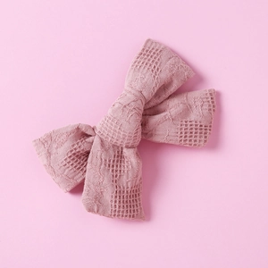 Detailed close-up of pink cotton plaid bow hair clip with textured waffle fabric detail