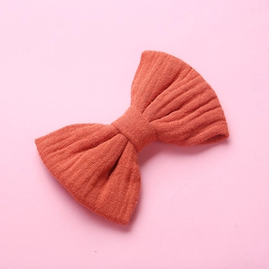 Trama dettagliata del fiocco per capelli in mussola di cotone rosso su sfondo rosa