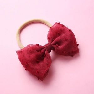 Détail du nœud en résille rouge à pois sur un bandeau bébé en nylon ultra doux