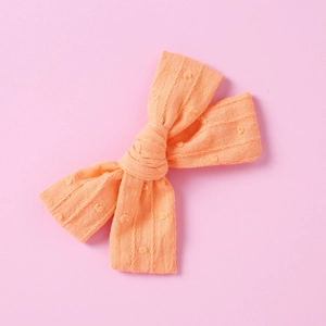 Detailed view of the textured coral cotton bow hair clip with dobby dot and stripe pattern