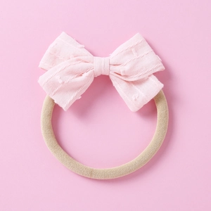 Detail of pink jacquard bow baby headband showing soft fabric texture and elastic nylon band