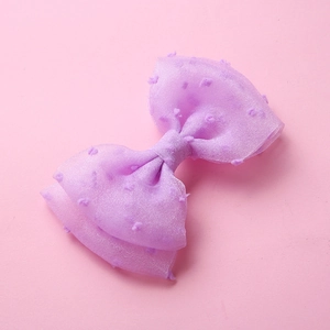 Détail de la barrette à nœud en tulle violet avec pois sur fond rose doux