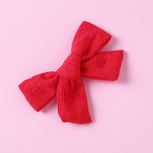 Close-up of red cotton plaid bow hair clip showing detailed weave texture and pattern