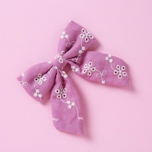 Détail d'un nœud papillon en coton violet avec broderie florale blanche pour fille