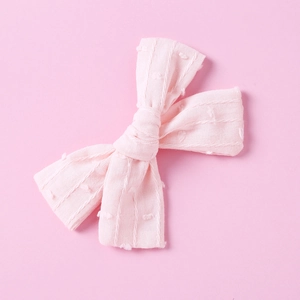 Close-up of pink cotton bow hair clip featuring textured jacquard dots and stripes