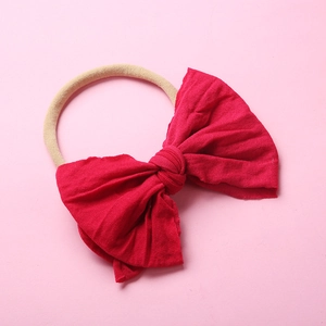 Vue détaillée du bandeau bébé avec nœud rouge et ruban en nylon souple sans couture