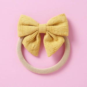 Détail du bandeau à nœud jaune évidé avec bande en nylon souple pour bébé et fille
