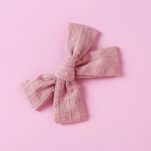 Close-up of pink cotton jacquard bow clip with textured stripes and 3D swiss dots