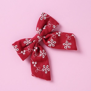 Détail du nœud de cheveux en coton rouge foncé avec broderie florale blanche