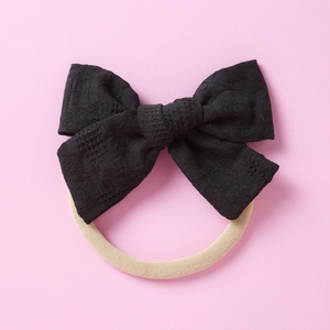 Détail d'un bandeau à nœud en dentelle noire avec un élastique en nylon beige doux