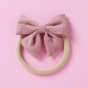 Gros plan du nœud rose en tissu gaufré sur un bandeau élastique pour bébés