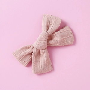 Detailed macro view of pink jacquard cotton fabric texture on kids bow hair clip