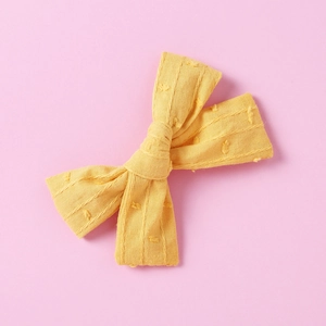 Detail of yellow cotton jacquard bow hair clip with textured dots and stripe patterns