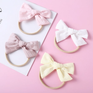 Quatre bandeaux pour bébé avec nœuds en coton aux couleurs douces sur fond rose