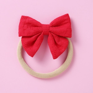 Détail d'un bandeau bébé en dentelle rouge avec ruban en nylon doux sur fond rose