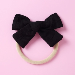 Détail du nœud à carreaux noirs avec élastique blanc crème sur un fond rose pastel