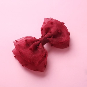Détail d'une barrette à cheveux nœud en tulle rouge foncé avec pois en velours