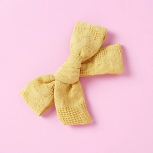 Close-up of mustard yellow handmade cotton bow hair clip with fine hollow texture