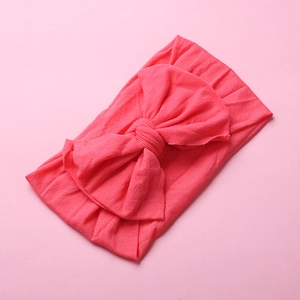 Close-up detail of soft elastic pink nylon headband featuring a large knotted bow design