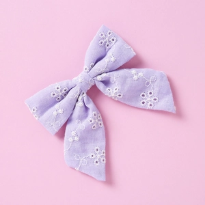Détail d'un nœud papillon en coton violet clair avec broderie florale blanche délicate
