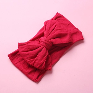 Detail of red elastic nylon infant headband featuring a soft double-layered bow knot