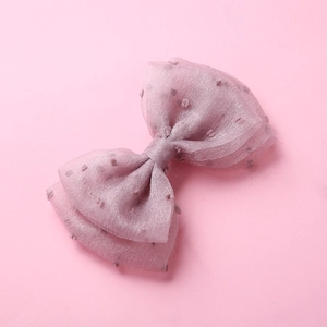 Détail d'une pince à cheveux rose en tulle avec pois texturés et nœud multicouche