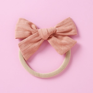 Gros plan d'un bandeau bébé avec nœud en coton rose et bande élastique souple sans couture