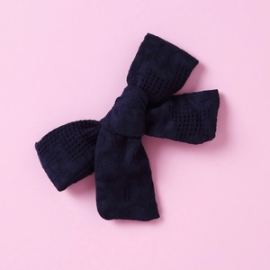 Detailed close-up of dark blue cotton plaid bow hair clip with jacquard fabric texture