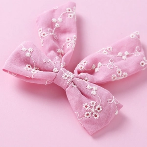 Gros plan d'une barrette rose en coton avec broderie anglaise florale et détails ajourés