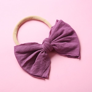 Détail du bandeau pour bébé avec grand nœud tricoté violet foncé et ruban en nylon souple
