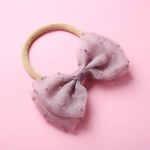 Détail du bandeau bébé en nylon souple avec un grand nœud en résille rose à pois