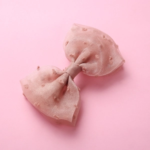 Vue macro d'une barrette à cheveux rose avec pois 3D et nœud en tulle à double épaisseur