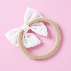 Détail d'un bandeau en dentelle blanche avec un ruban en nylon beige élastique doux