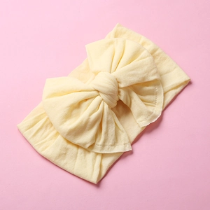 Detail of soft yellow nylon baby headband featuring a large double-layer knitted bow