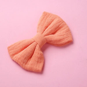 Dettaglio della trama in mussola di cotone rosa pesca del fiocco per capelli da bambina