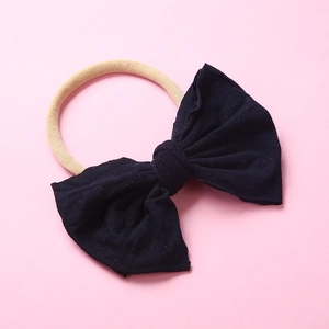 Détail d'un bandeau pour bébé en nylon souple avec un grand nœud noir en tissu doux