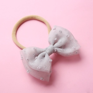 Détail du bandeau en nylon pour bébé avec nœud en maille grise à pois sur rose