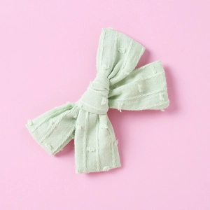 Detailed texture of a mint green cotton jacquard bow clip with raised polka dot pattern