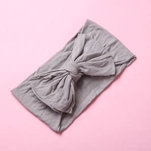 Detail view of soft nylon baby headband with a large dusty purple bow tie on pink background
