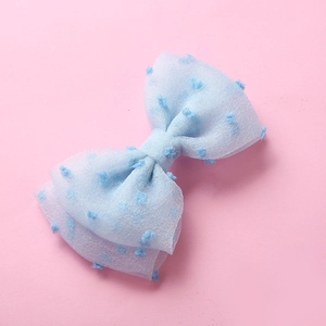 Détail d'un nœud papillon en maille bleu clair avec pompons pour filles et bébés