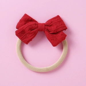 Soft nylon infant headband with a red textured jacquard bow on a pink background