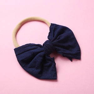 Détail d'un nœud en tricot bleu marine et bandeau en nylon beige pour bébé