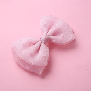 Détail d'une pince à cheveux nœud en tulle rose avec texture à pois pour enfants