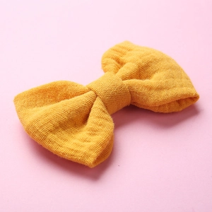 Dettaglio della trama del fermaglio a fiocco in mussola di cotone giallo per bambina