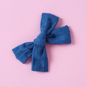 Detail of navy blue cotton bow hair clip featuring waffle texture fabric on pink background