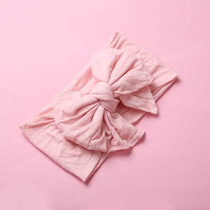 Close-up of soft pink nylon baby headband with large double-layered swallowtail bow knot